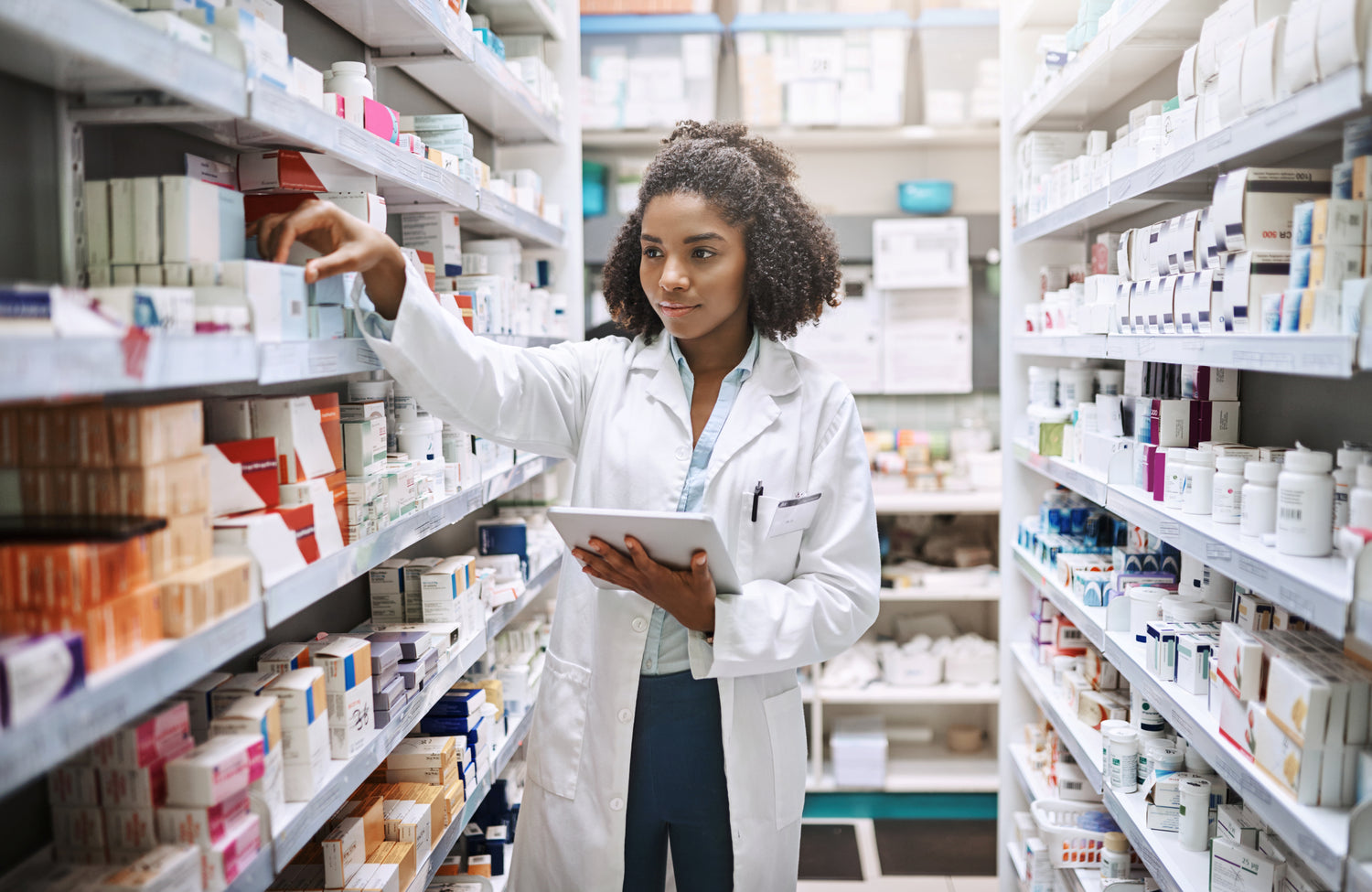 Pharmacists with tablet removing medication from shelf
