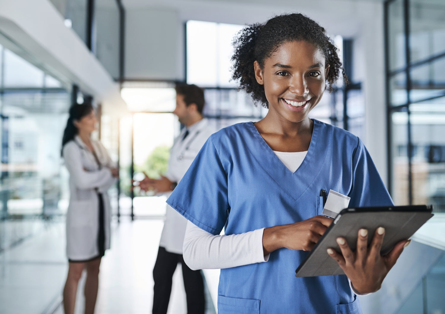 Smiling woman in scrubs holding tablet