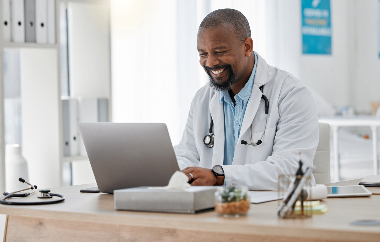 Smiling doctor working on laptop