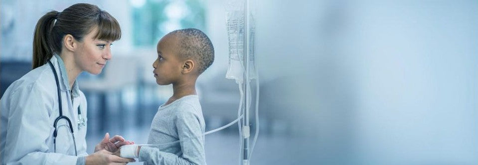 Doctor speaking to young child with IV bag