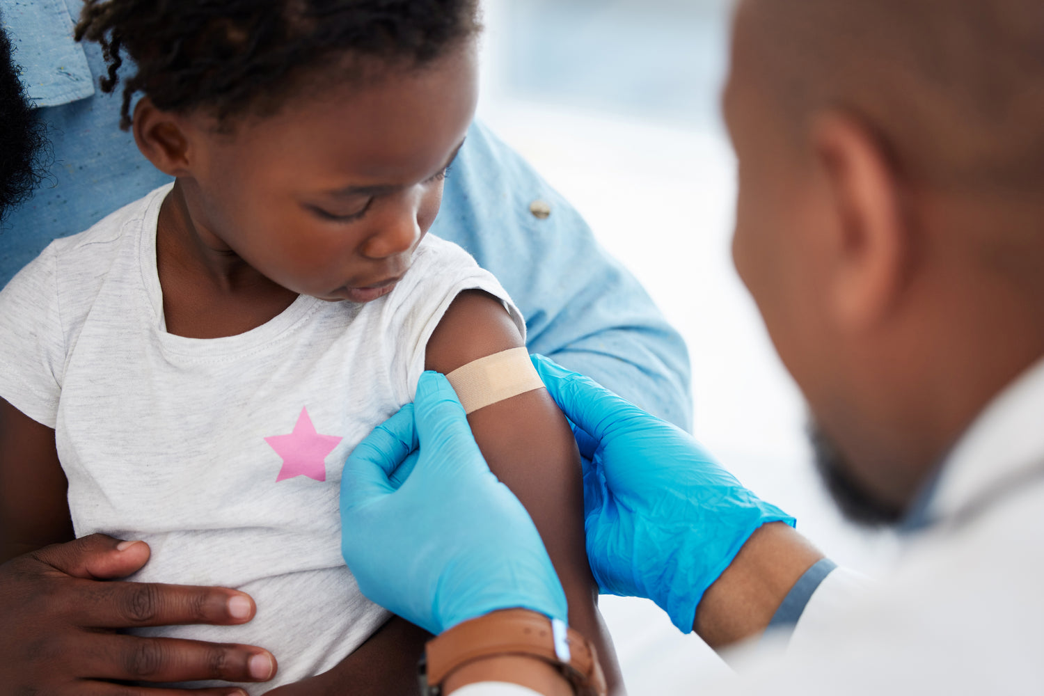 Doctor placing bandage on toddler's arm