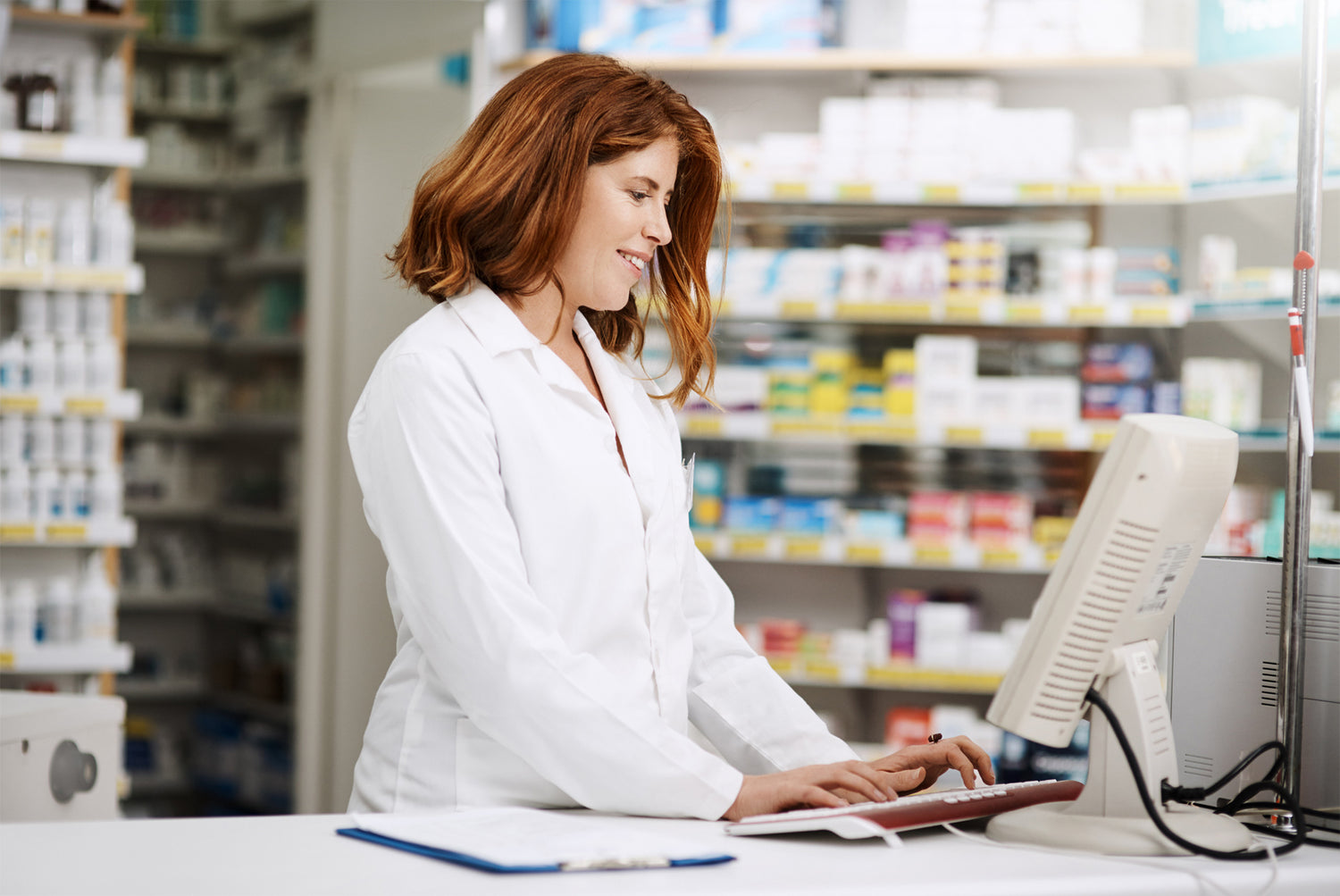 Pharmacist working in retail pharmacy. Shelves with medications in background